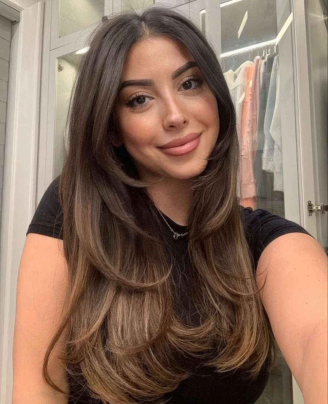 Long dark brunette butterfly haircut with long curtain bangs and curled ends plus caramel balayage.