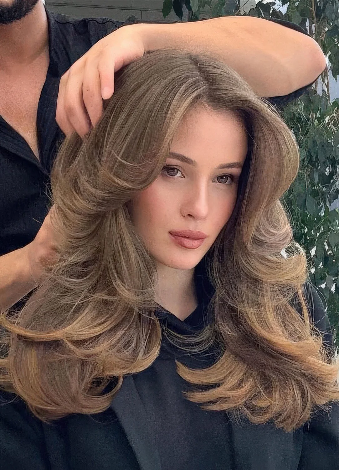 Bronde butterfly haircut with long curtain bangs and curled ends.