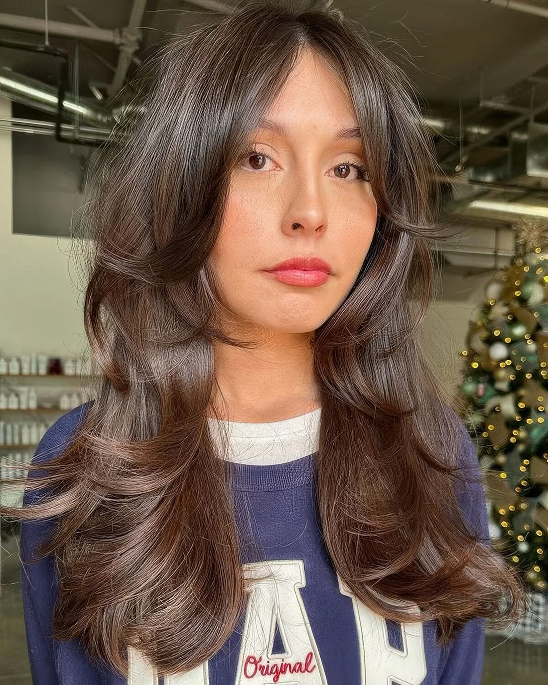 Dark brown long butterfly haircut with long curtain bangs, curled ends and volume.