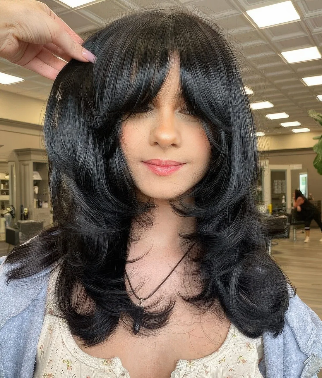 Medium black butterfly haircut with curtain bangs and curled ends and a shiny touch.