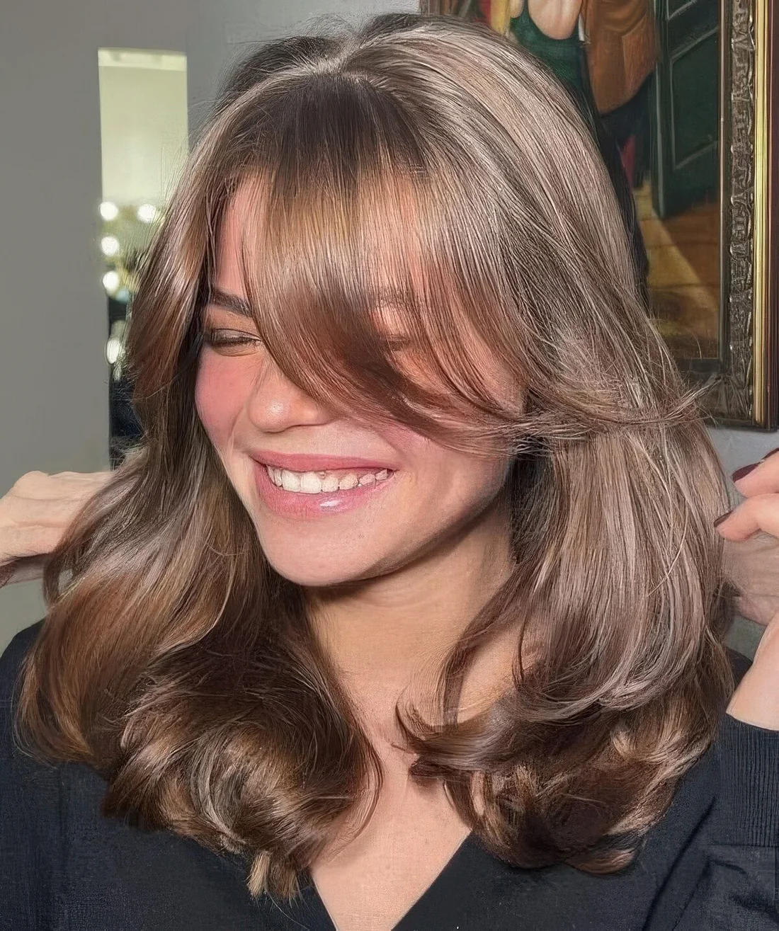 Shiny brown butterfly haircut with curtain bangs and a bit of waves to make it more dimensional.