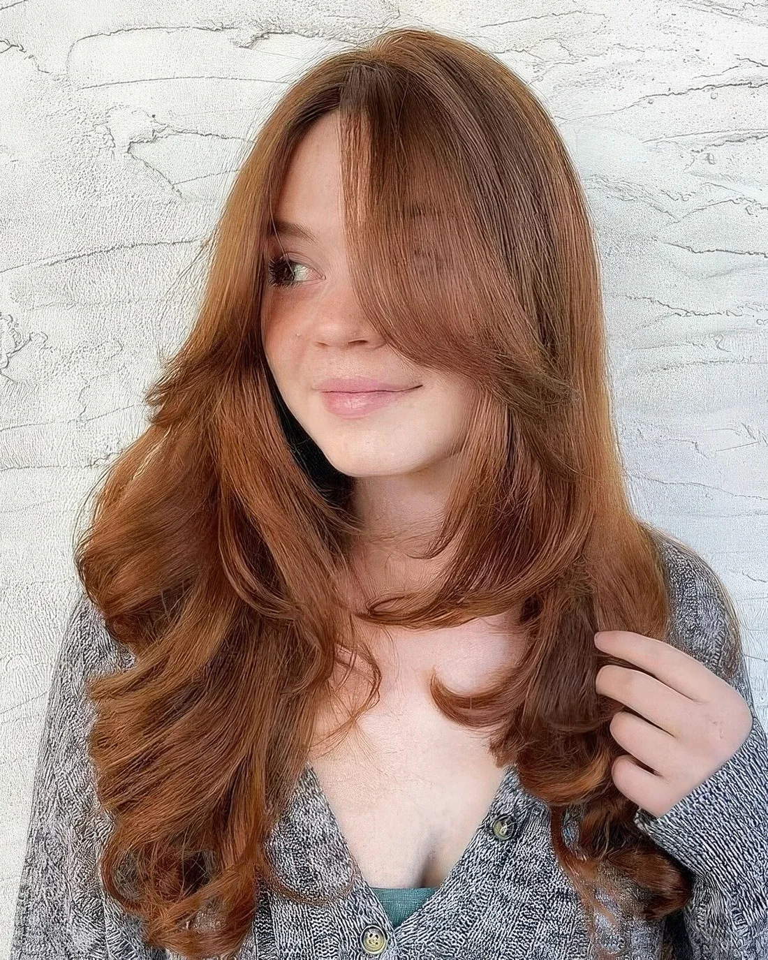 Long ginger hair with curtain bangs and curved ends plus a lot of volume.