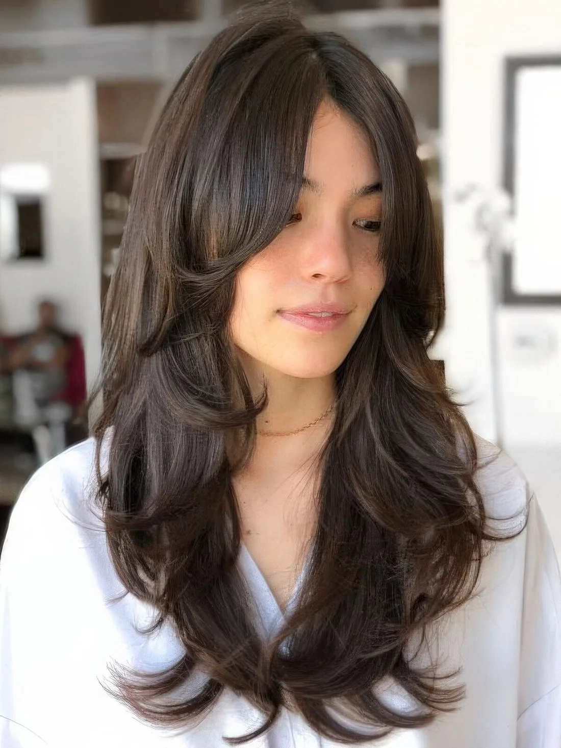 Dark brunette long butterfly haircut with wavy ends.
