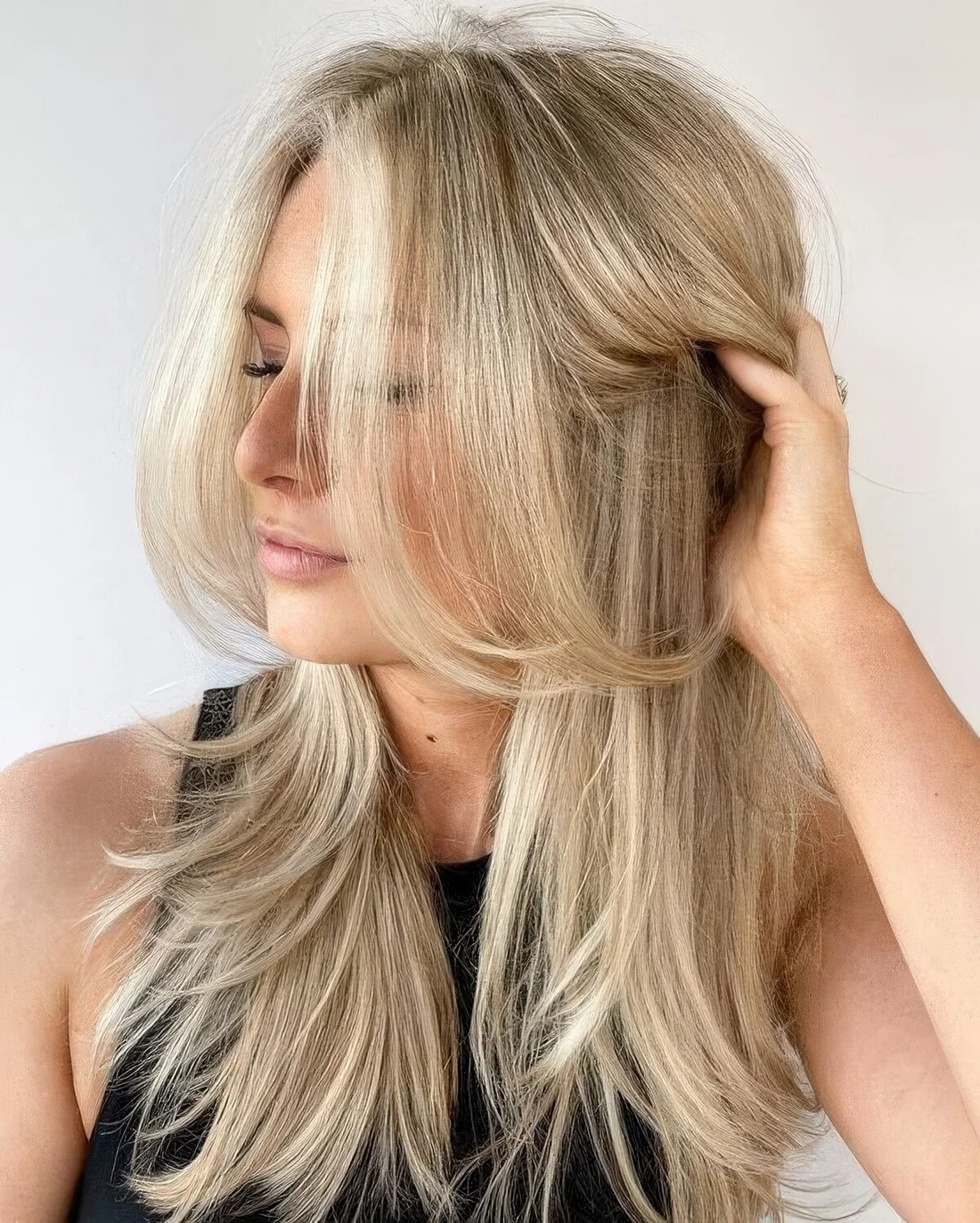 Bleached blonde butterfly haircut with curled ends and a bit of volume.