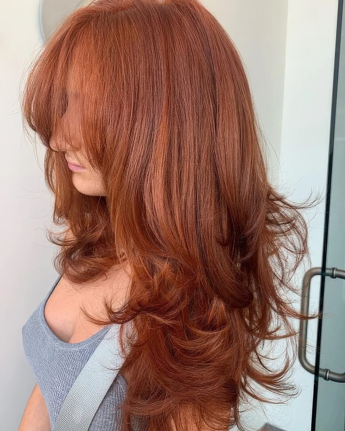 Breathtaking long red butterfly haircut with a lot of volume, wispy bangs and curled ends.