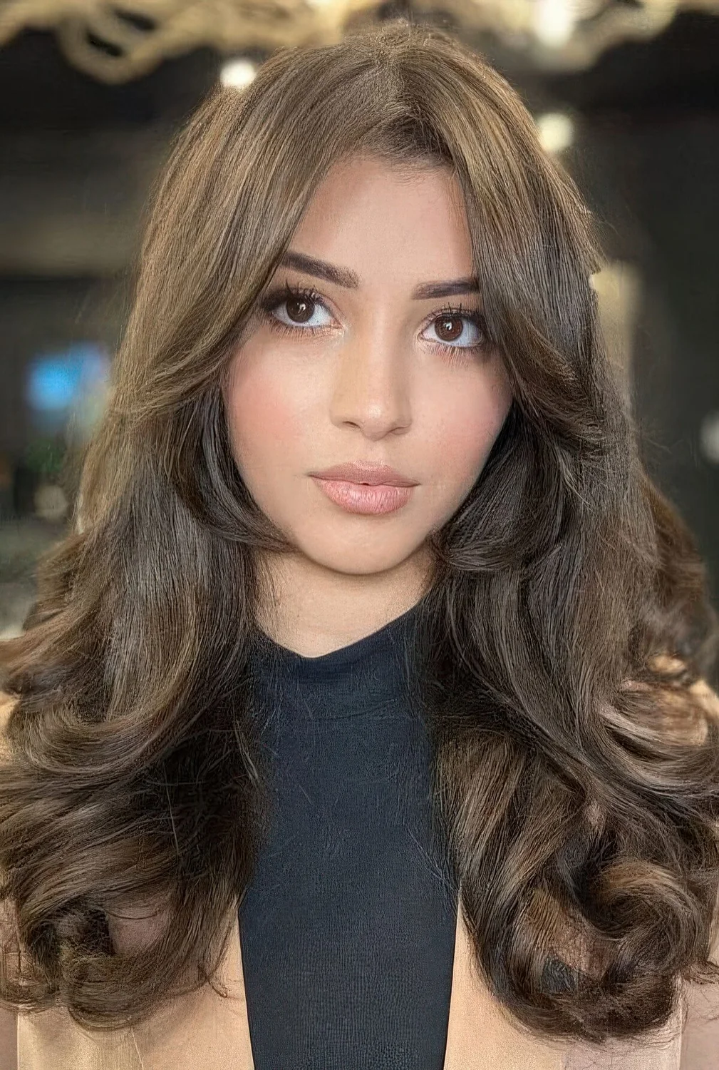 Brunette butterfly haircut with curtain bangs and curls plus volume.