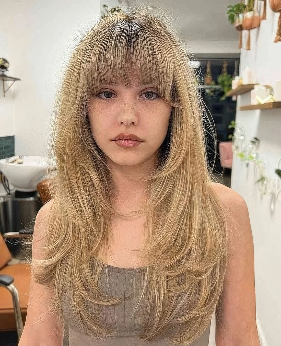 Buttefly haircut done on honey blonde hair with layered bangs and a lot of feathered layers.