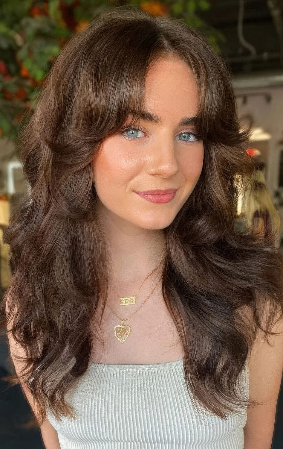 Brunette butterfly haircut with curtain bangs and waves.