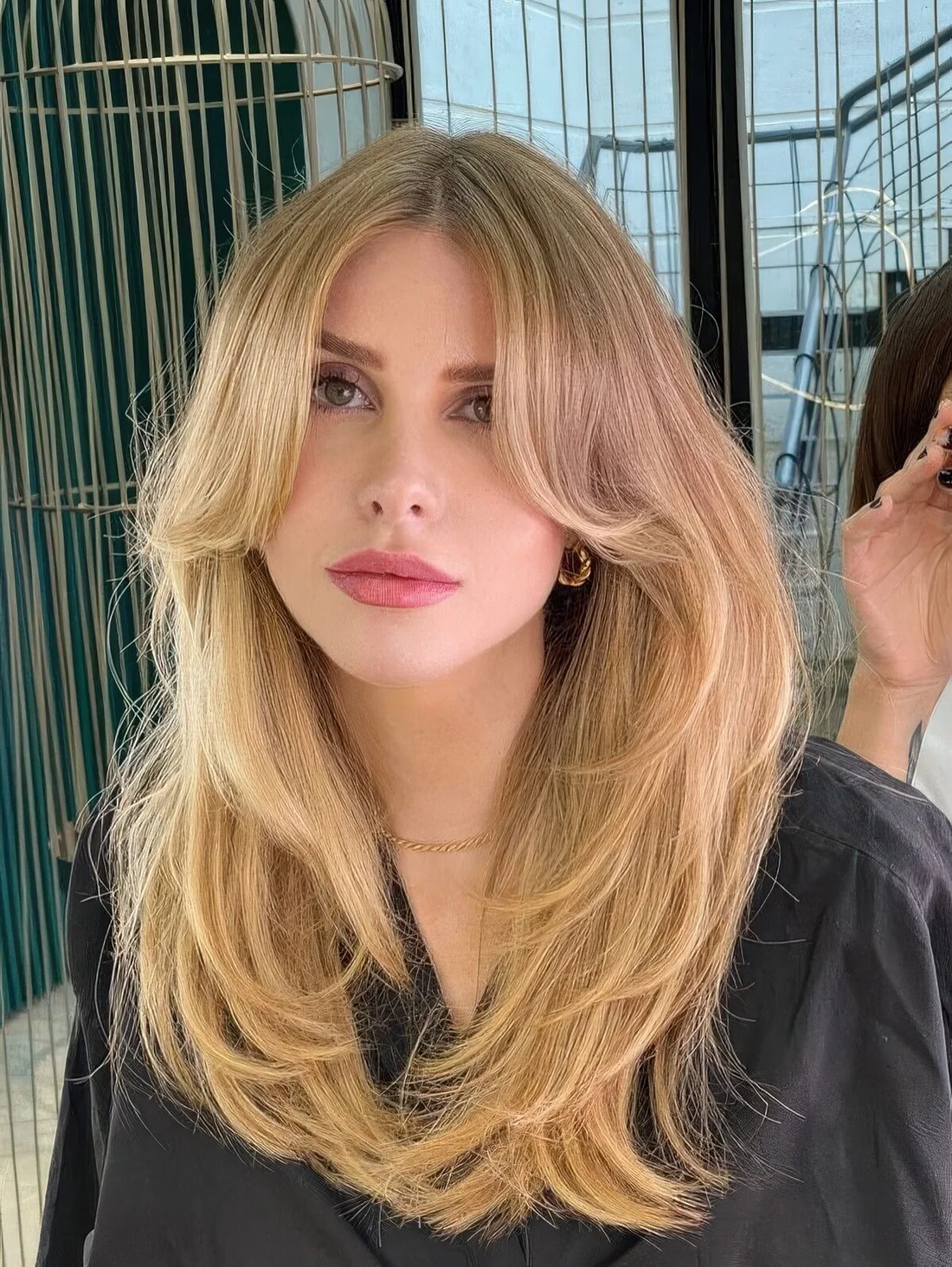 Fab blonde butterfly haircut with a darker root, curtain bangs and some ends curved.