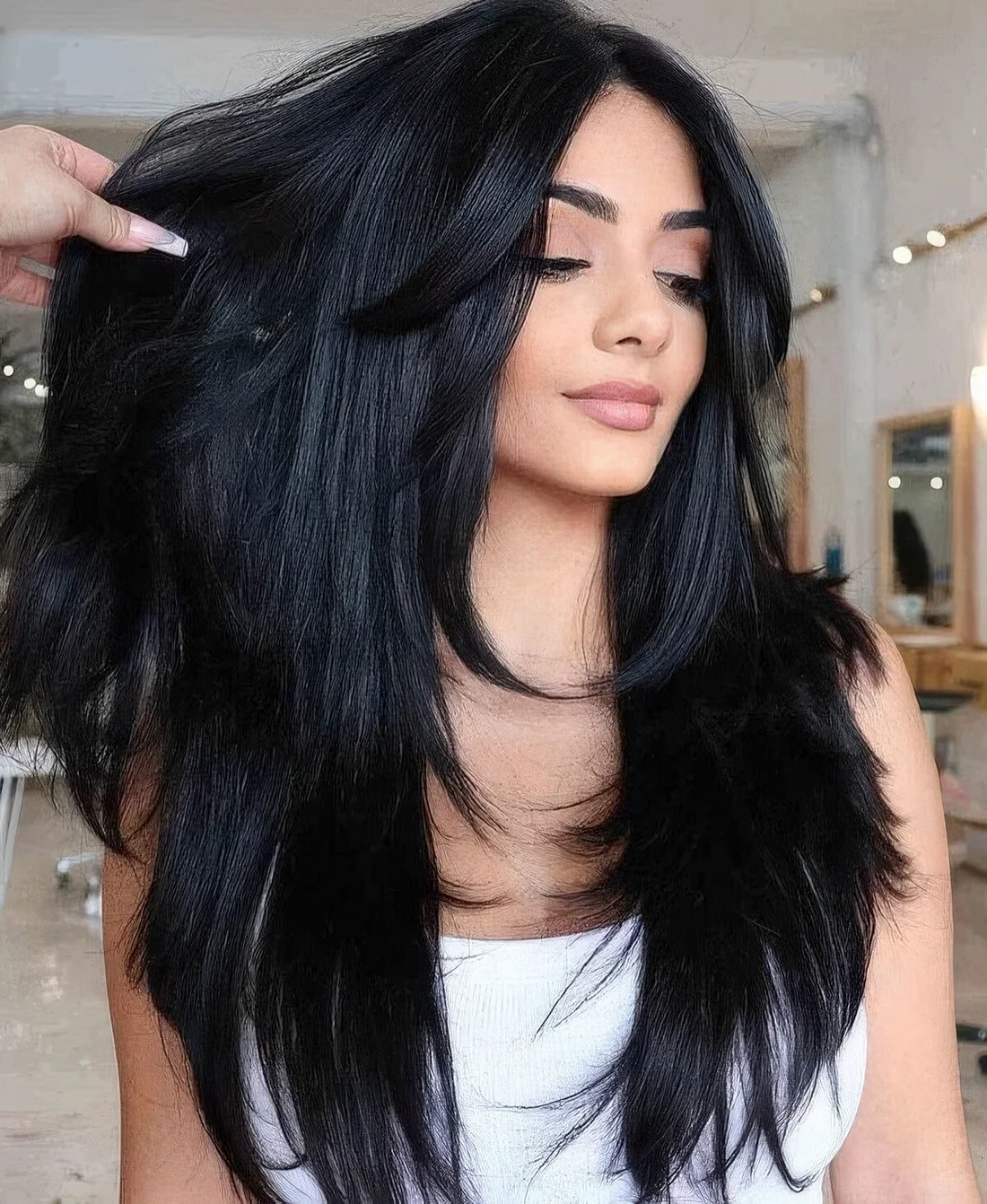 Long black butterfly haircut with curtain bangs and curled ends.
