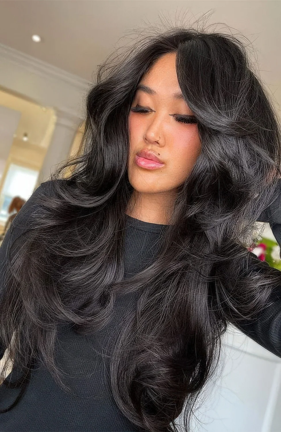 Black butterfly haircut with curled ends, a lot of volume and curtain bangs.