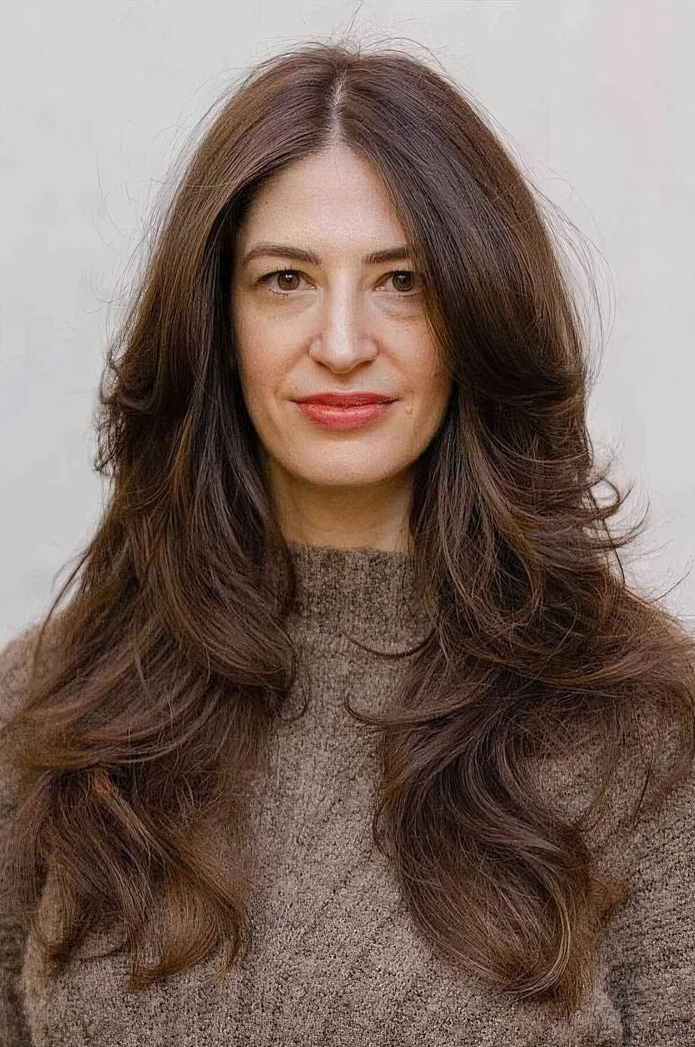 Dark brunette butterfly haircut with long curtain bangs and waves.