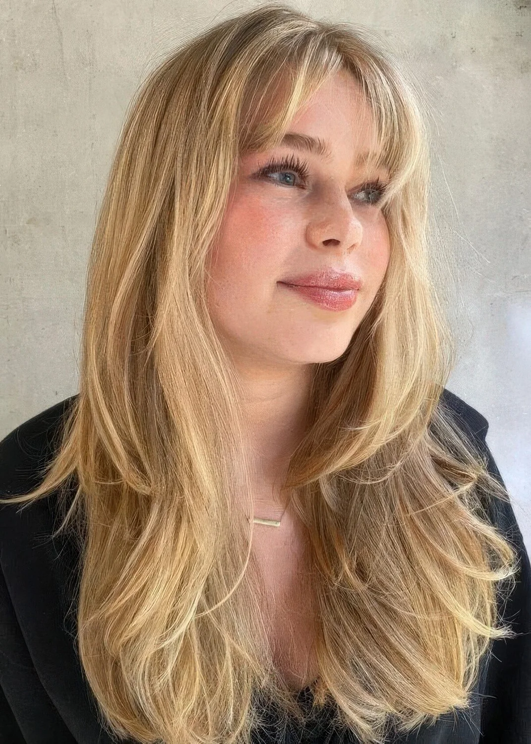 Textural and dimensional blonde butterfly haircut with curtain bangs and volume.