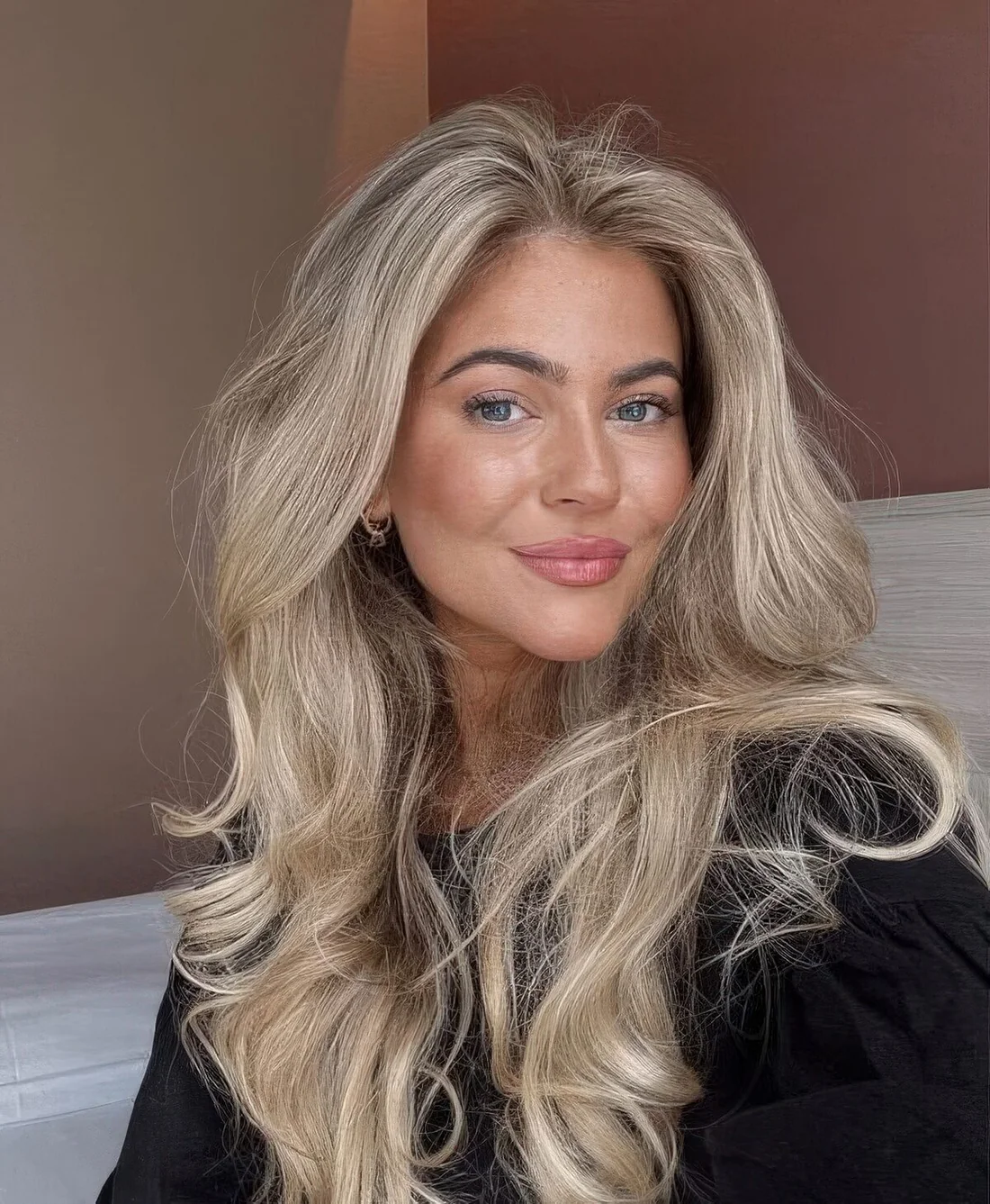 Long and fluffy blonde butterfly haircut with balayage, with curled ends and a lot of volume.