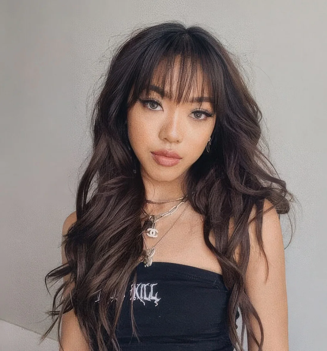 Long dark brunette butterfly haircut with wispy bangs, volume and waves.