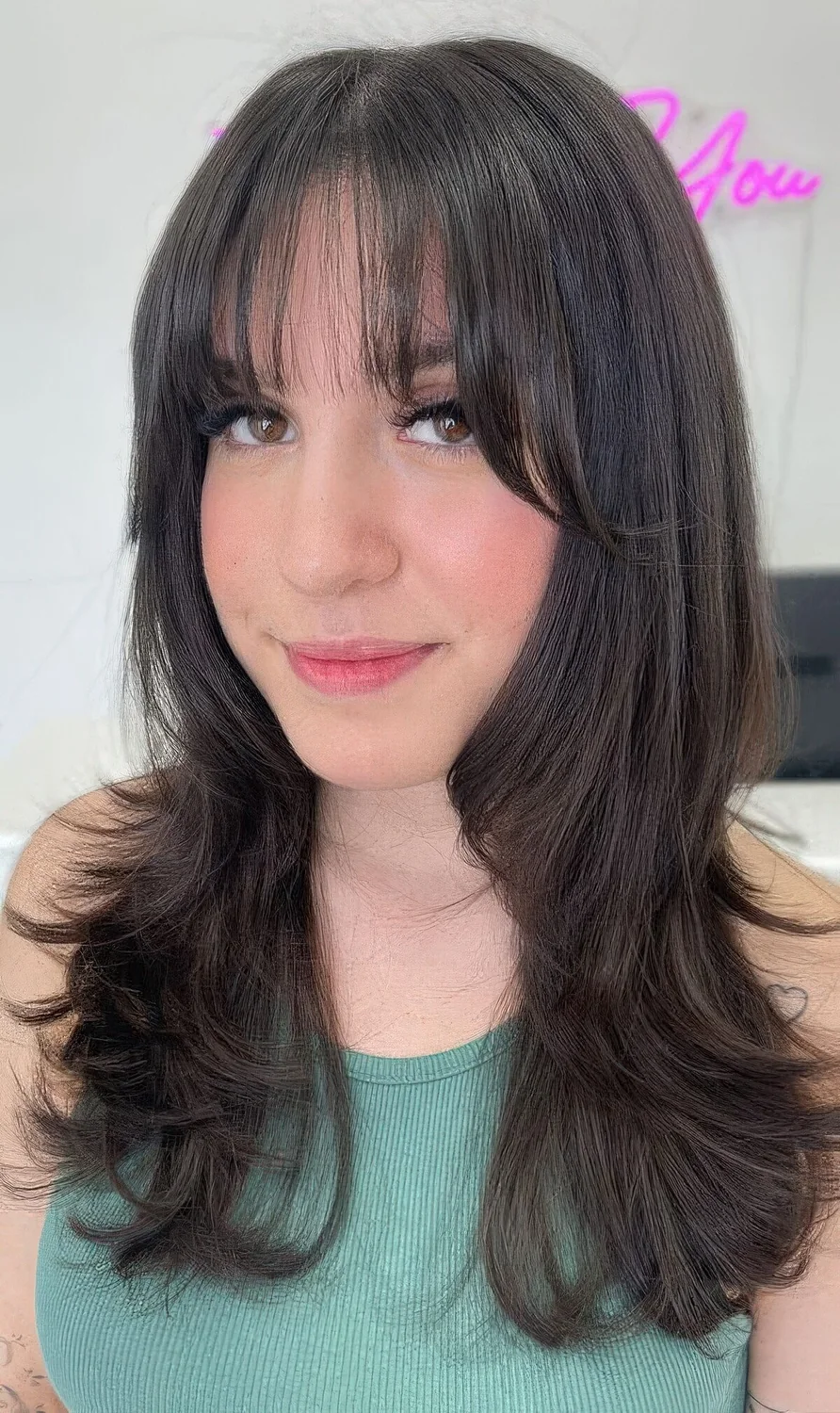 Long dark brunette butterfly haistyle with wispy bangs and curled ends.