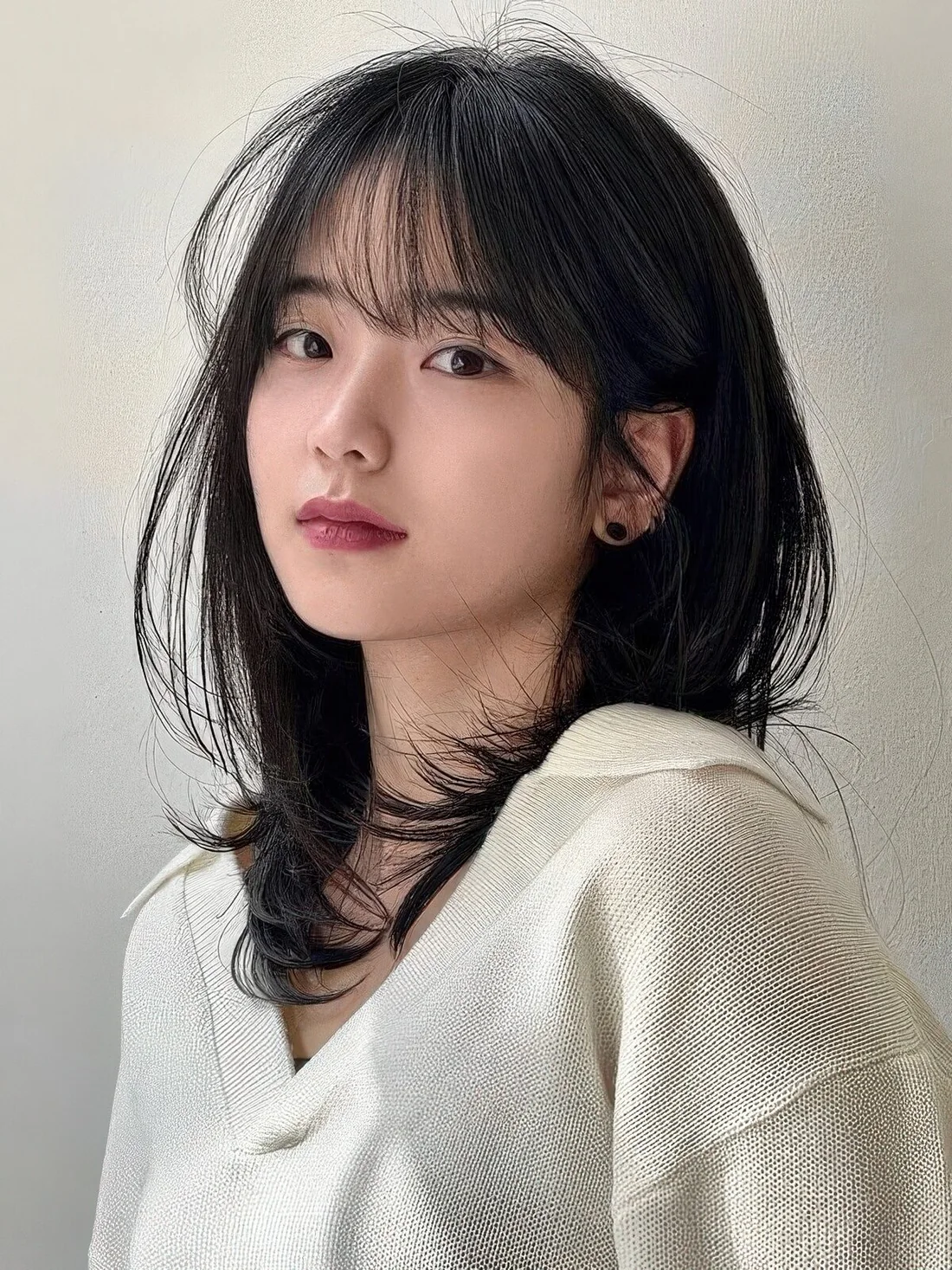 Black butterfly medium-length haircut with wispy bangs and curled ends.