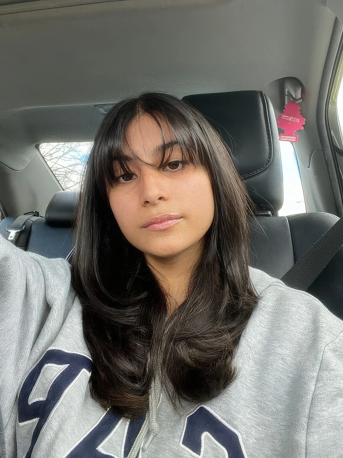 Medium butterfly haircut in almost black and with wispy bangs plus curled ends.