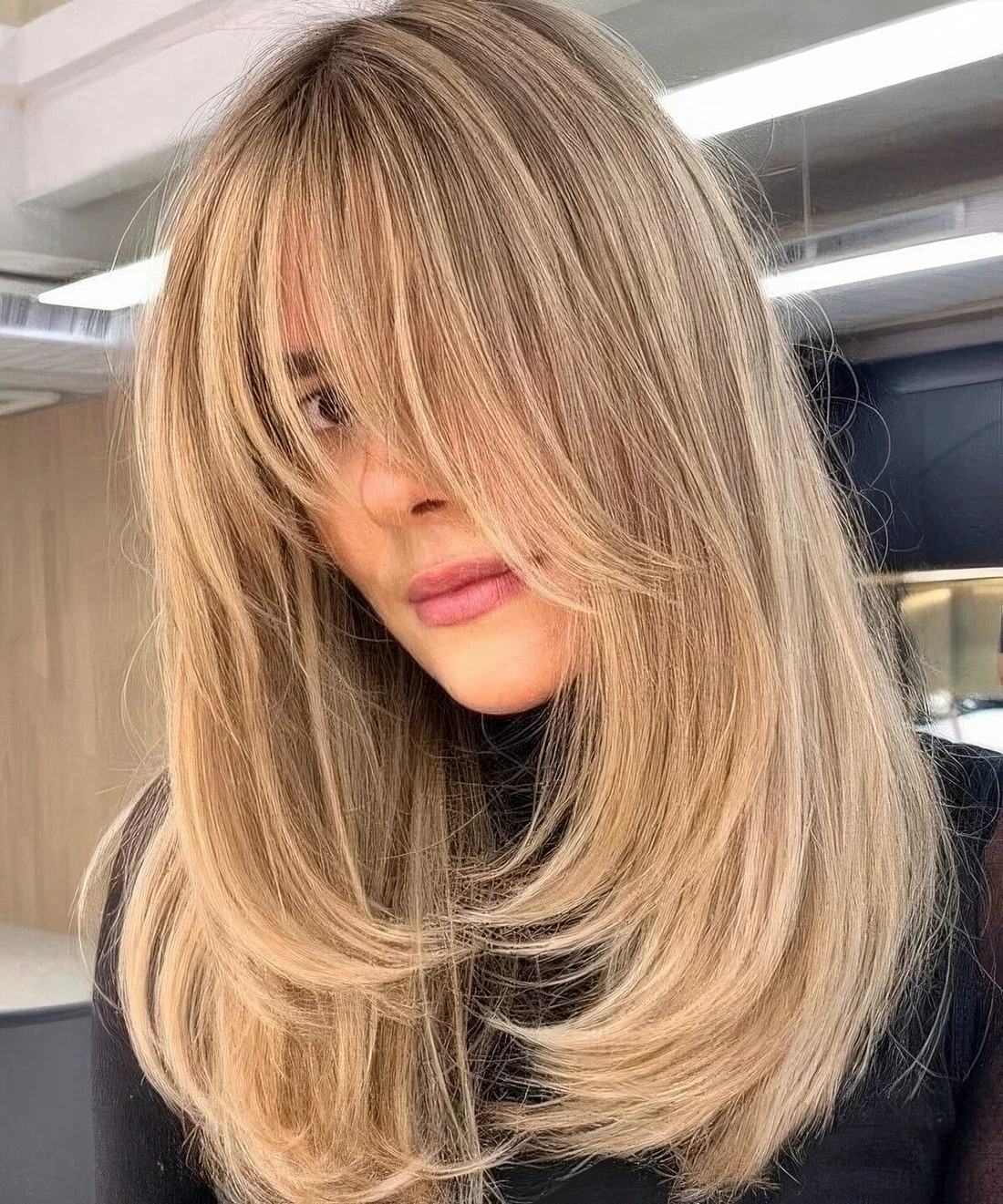 Medium blonde butterfly locks with side and wispy bangs both to frame the face.