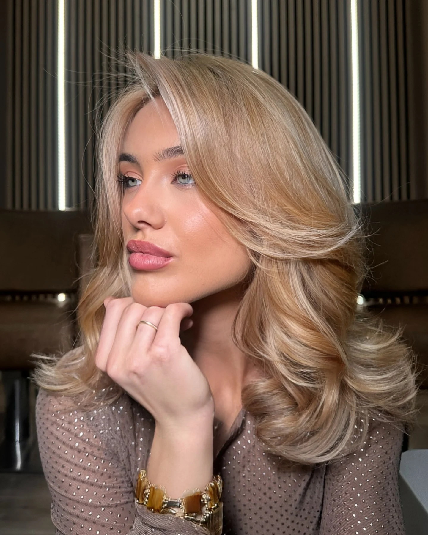 Woman with blonde butterfly layers, curled ends, and long curtain bangs
