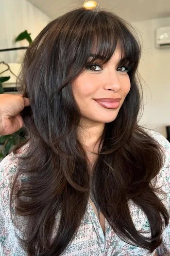 chest wavy black layers with curtain fringe shown as a butterfly haircuts with bangs idea