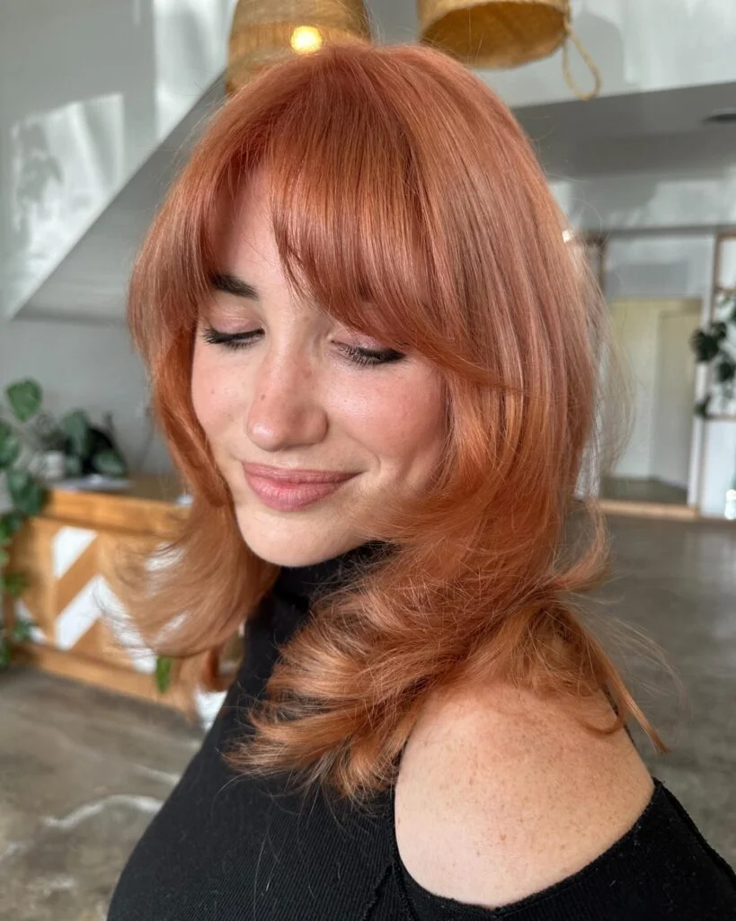 chest wavy copper layers with curtain fringe shown as a butterfly haircuts with bangs idea