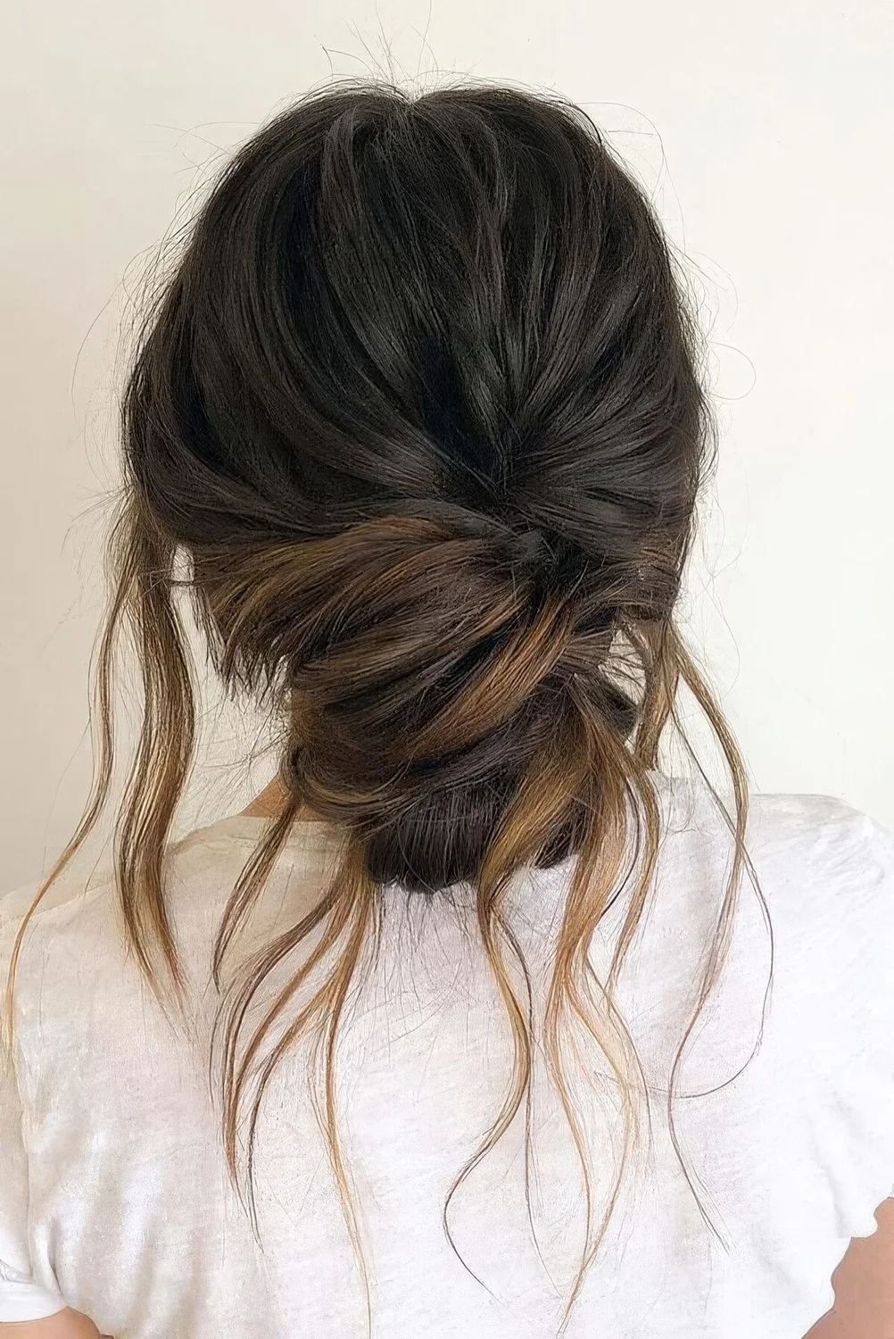Casual and messy low bun with a volume on top, hair down.
