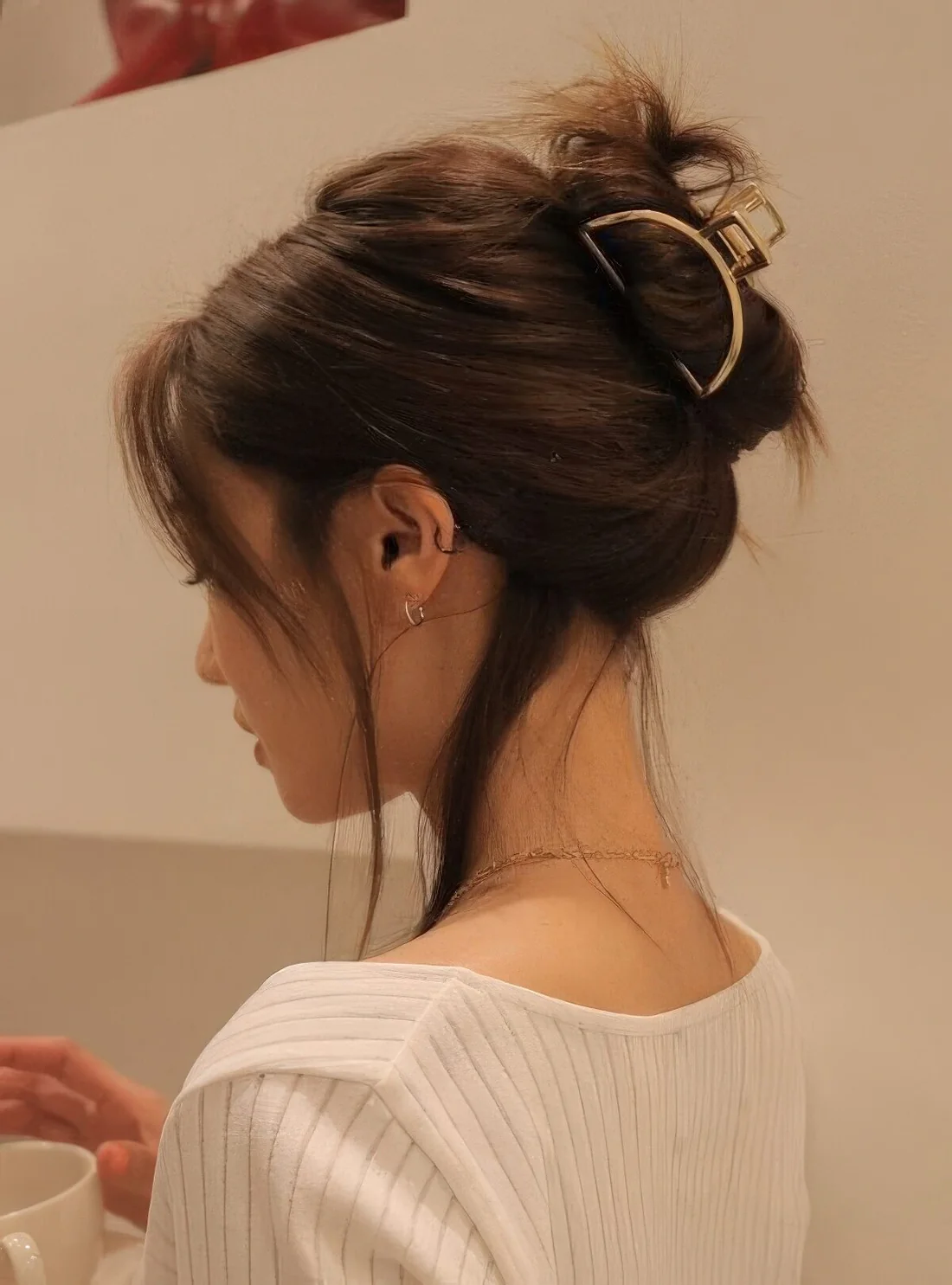 Casual volumetric updo with a gold hair clip, some face-framing bangs and a volume on top.