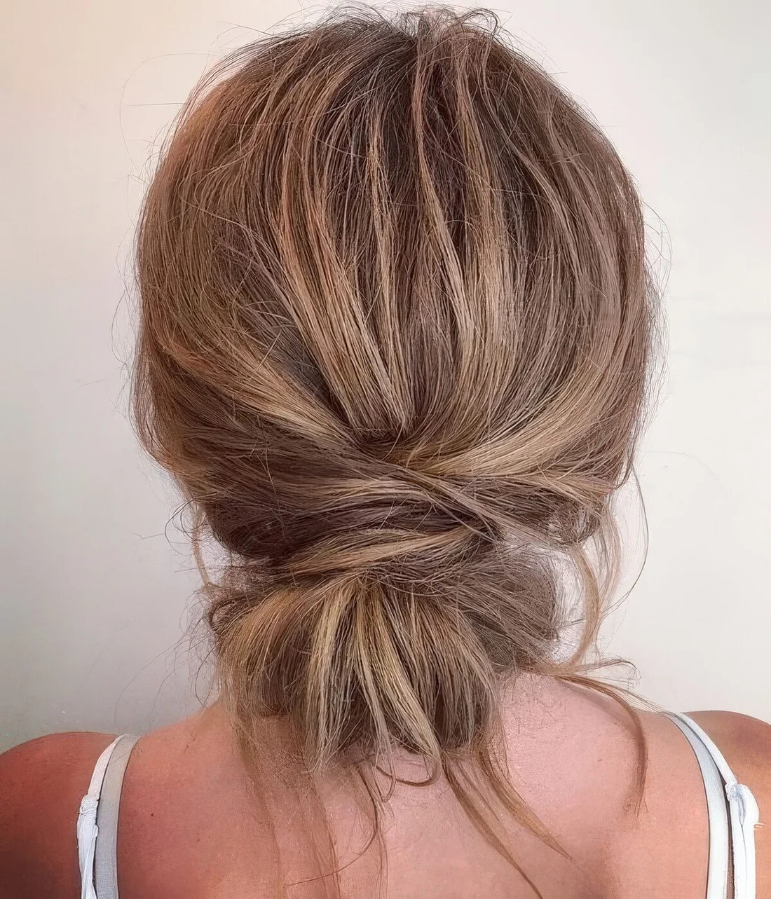 Messy and textural low bun with a messy volumetric top and some hair down for medium to long hair.