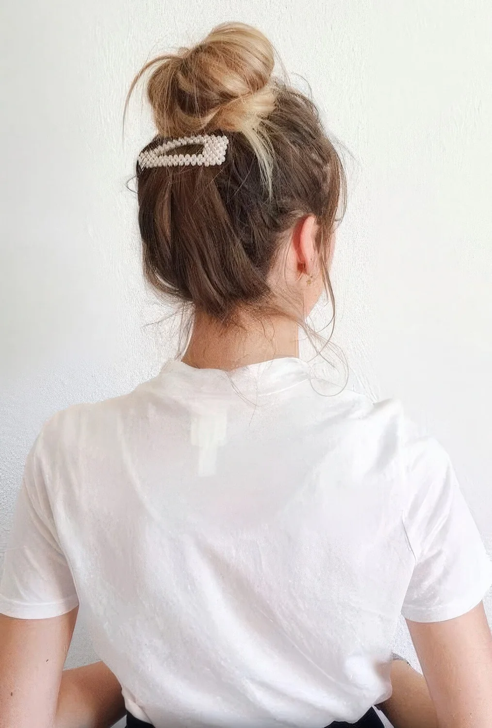 Messy ballerina top knot with messy hair around and a pearl clip to make a slight accent and secure the hair.