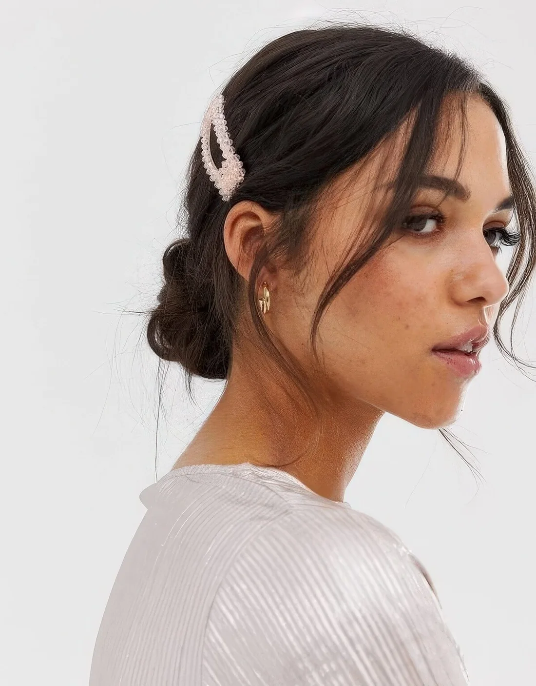 Messy low bun with a volumetric top and face-framing hair plus a hair clip for a small and cute accent.