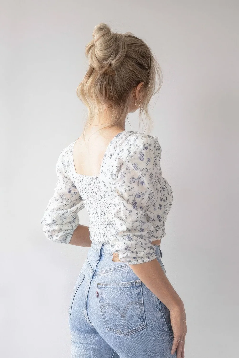 Messy top knot with a volumetric top, some hair down and face-framing bangs.