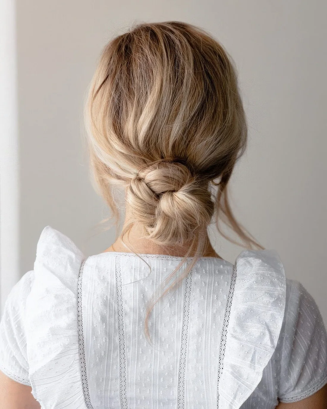 Messy twisted low bun with a volumetric top and some face-framing bangs.
