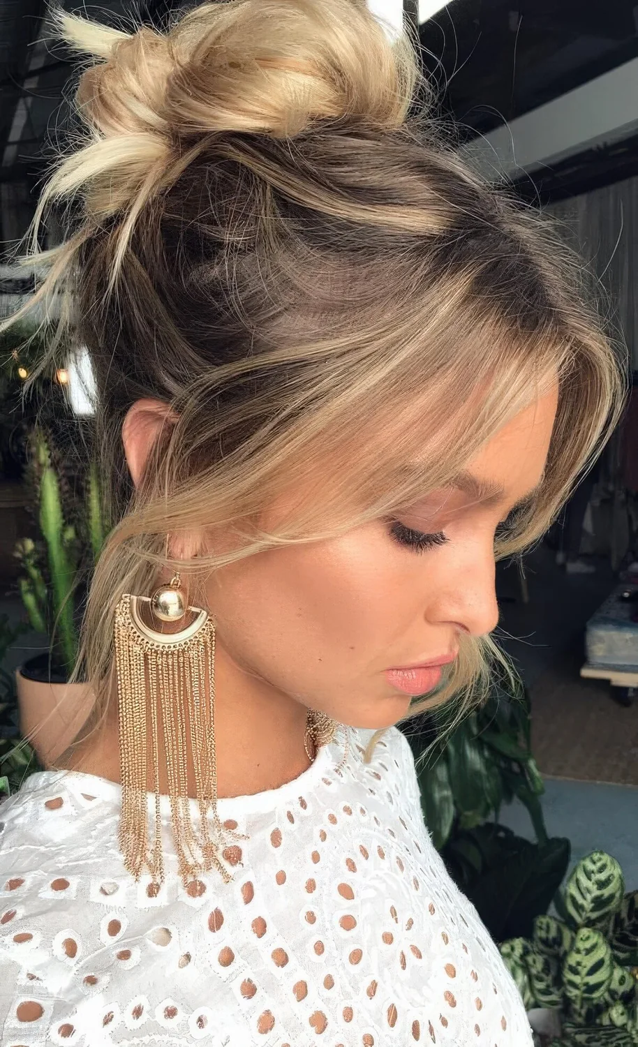 Mesys ballerina top knot with a messy top, face-framing bangs.