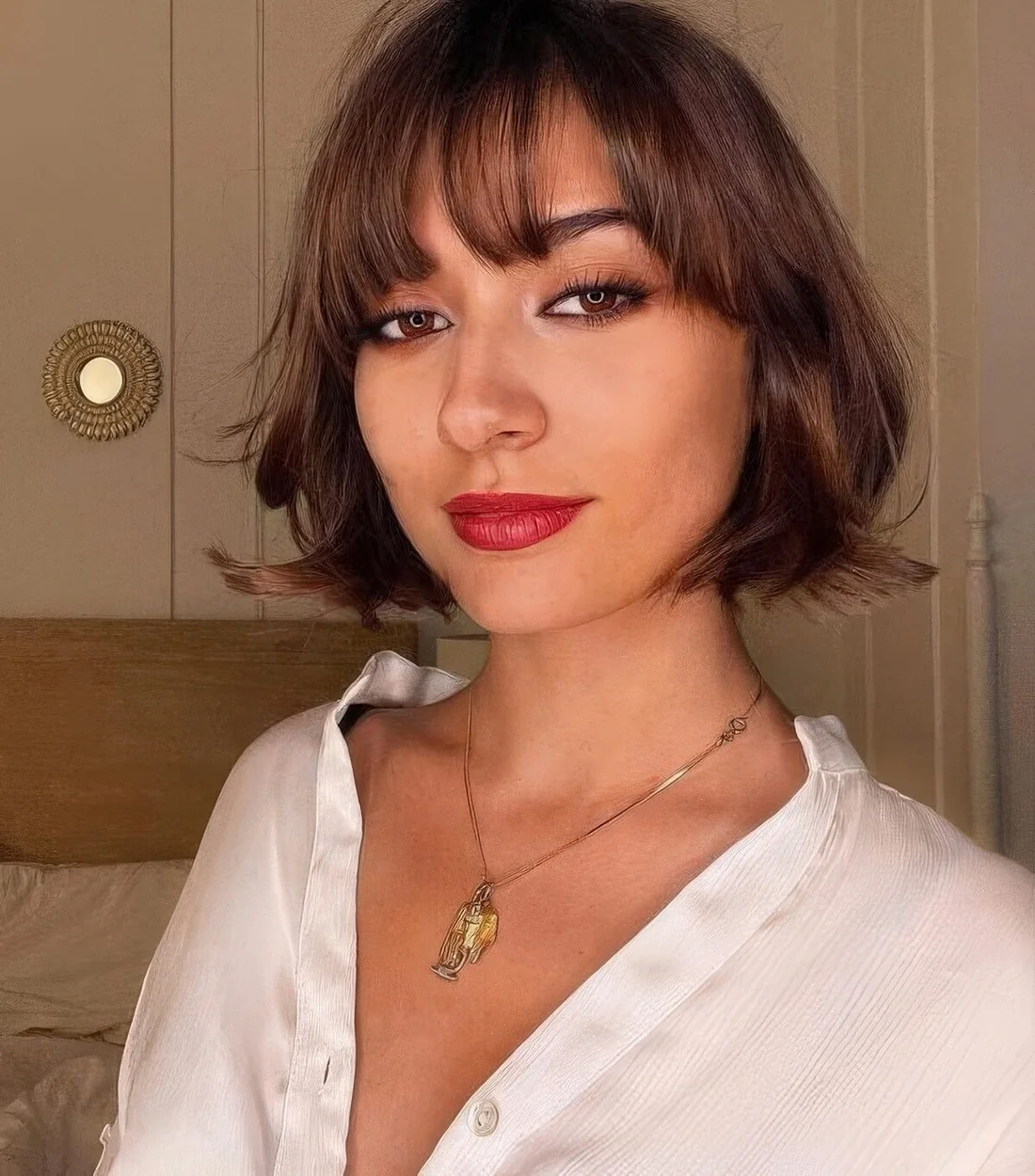 Brunette chin-length bob with wispy bangs and waves.