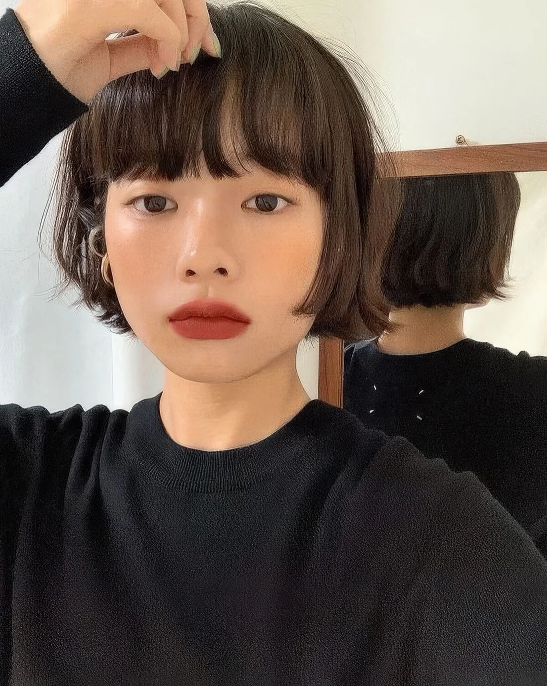 Brunette ear-length bob with outgrown bangs and messy texture.