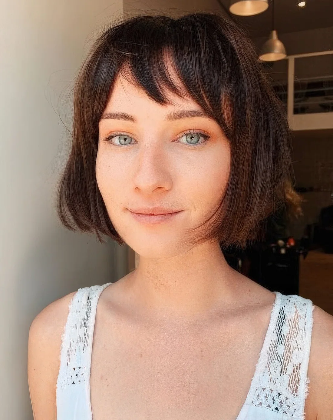 Dark brunette chin-length bob with wispy bangs.