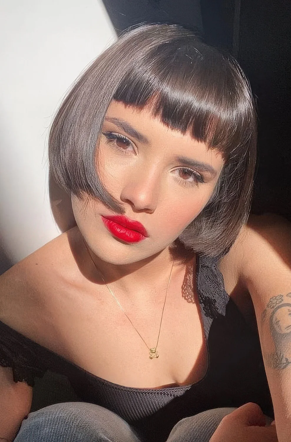 Dark brunette ear-length bob with baby bangs and curled ends plus a shiny finish.