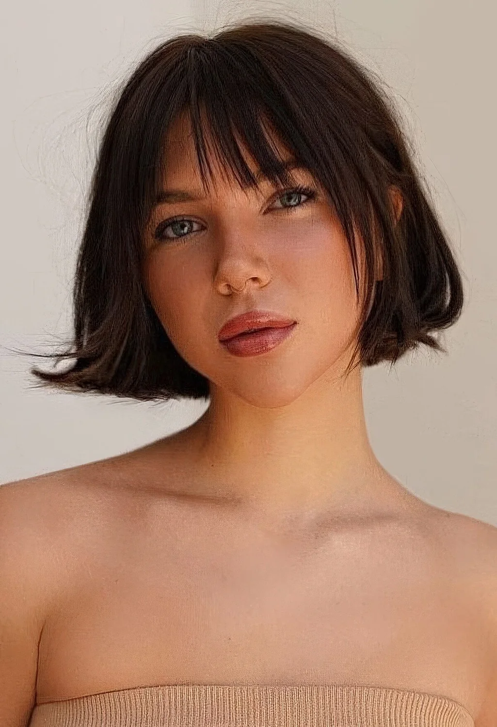 Dark brunette jaw-length bob with face-framing layers and wispy bangs and a bit of volume.