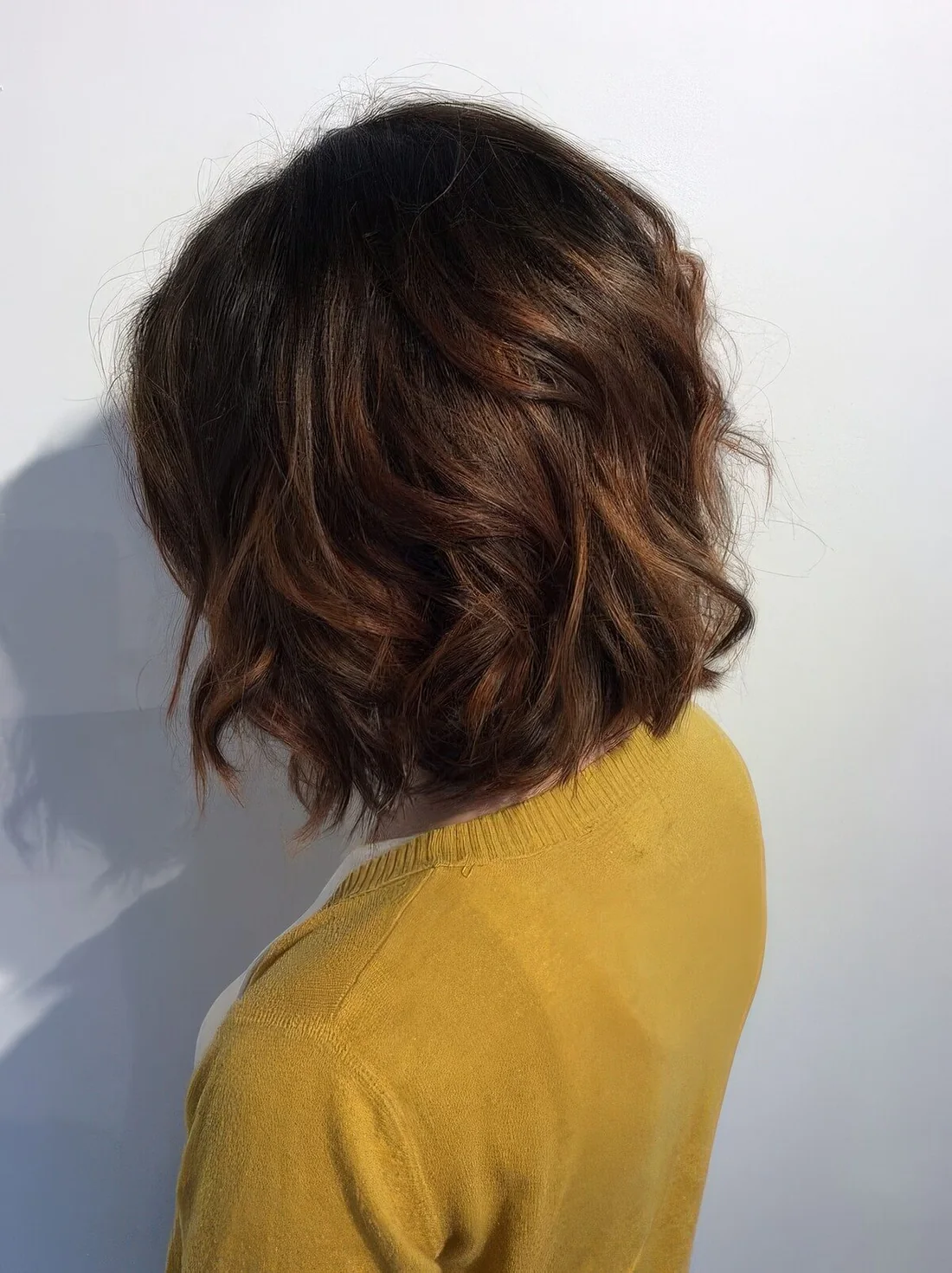 Long chestnut bob with messy waves and volume.