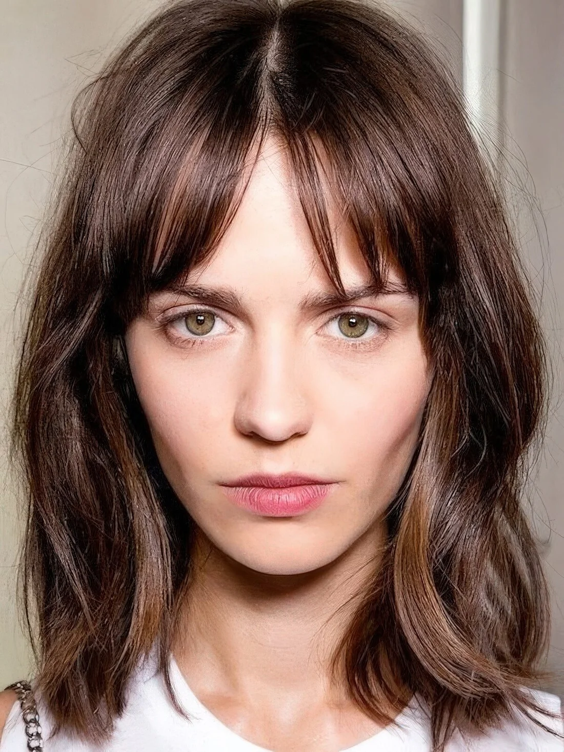 Messy layered brown shoulder-length bob with highlights and bottleneck bangs.