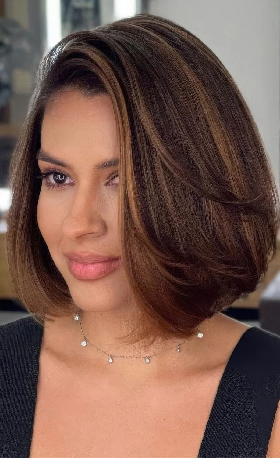 Mid chestnut bob with caramel balayage and curled ends, with volume and straight hair.