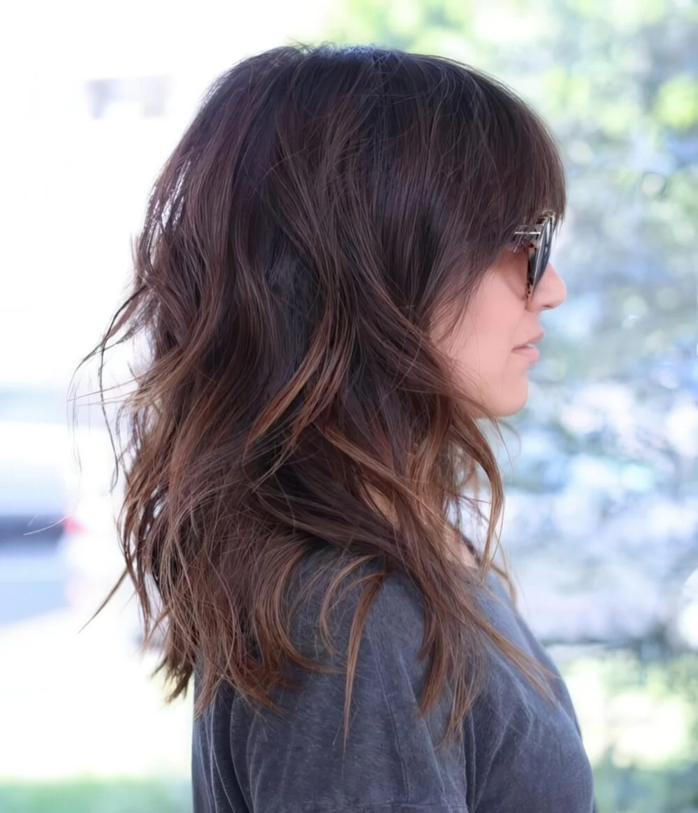 Medium-length layered hair with caramel highlights.