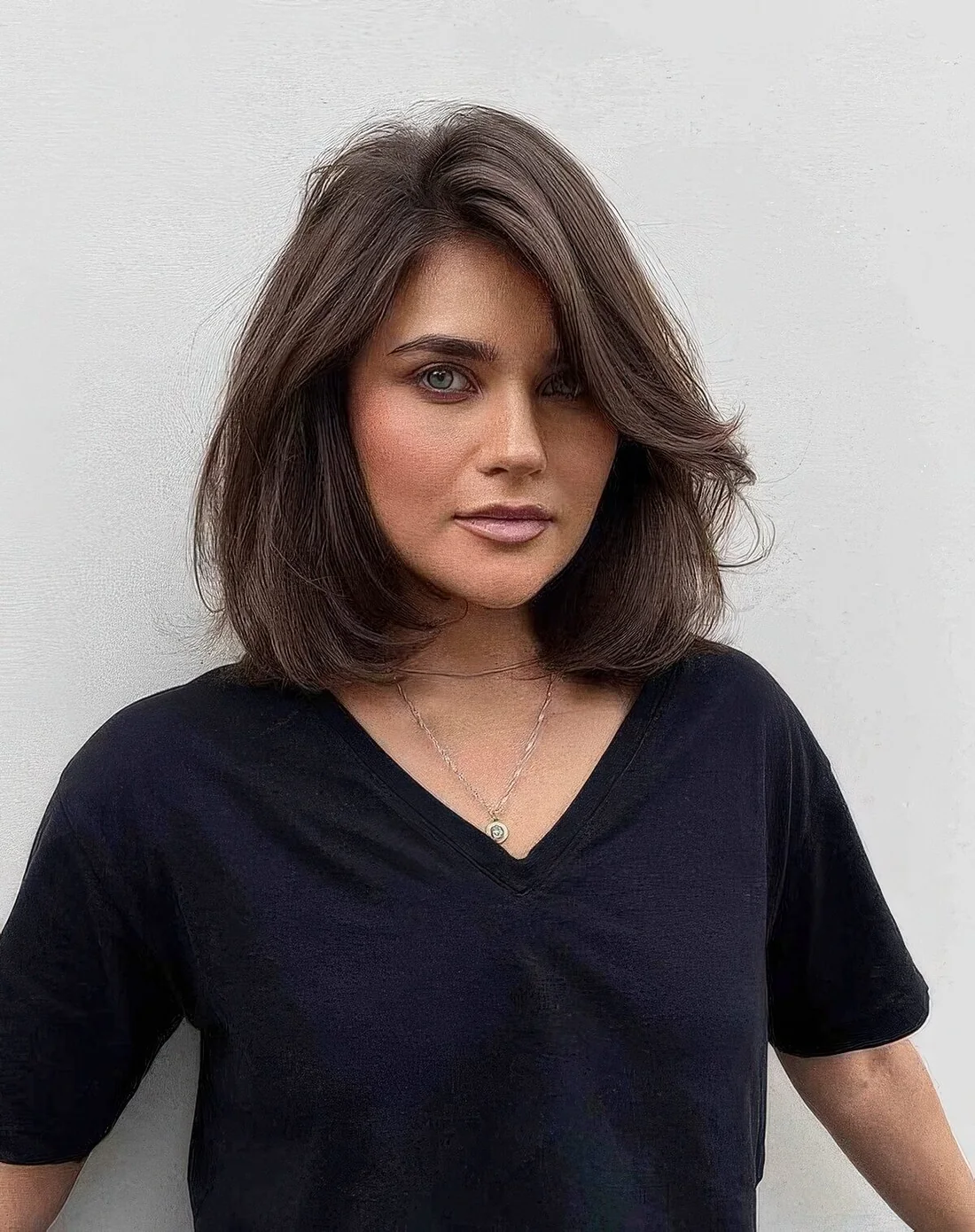 Brown long bob with side bangs, messy waves and a lot of volume.