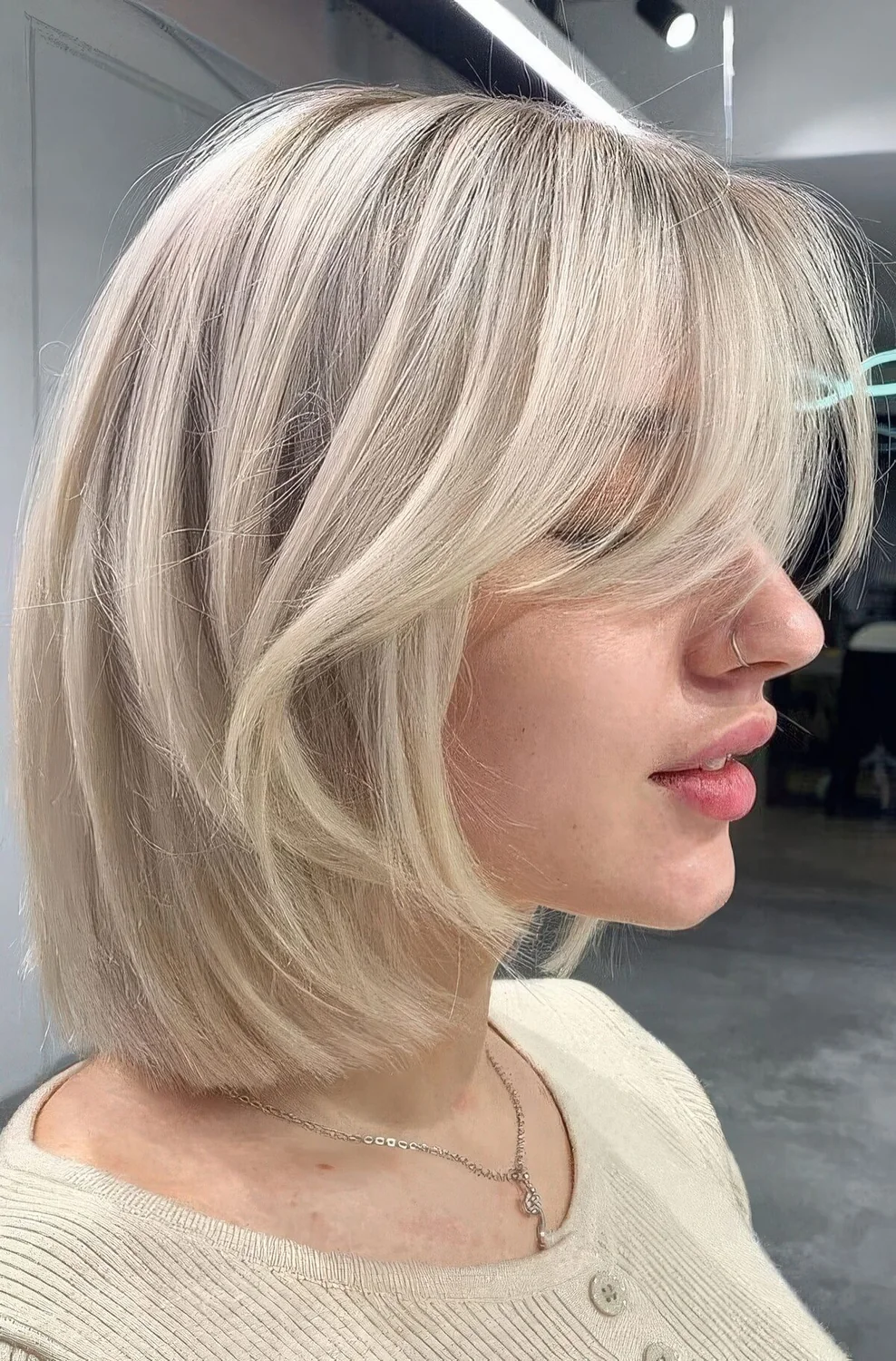 Chic icy blonde long bob with curtain bangs.