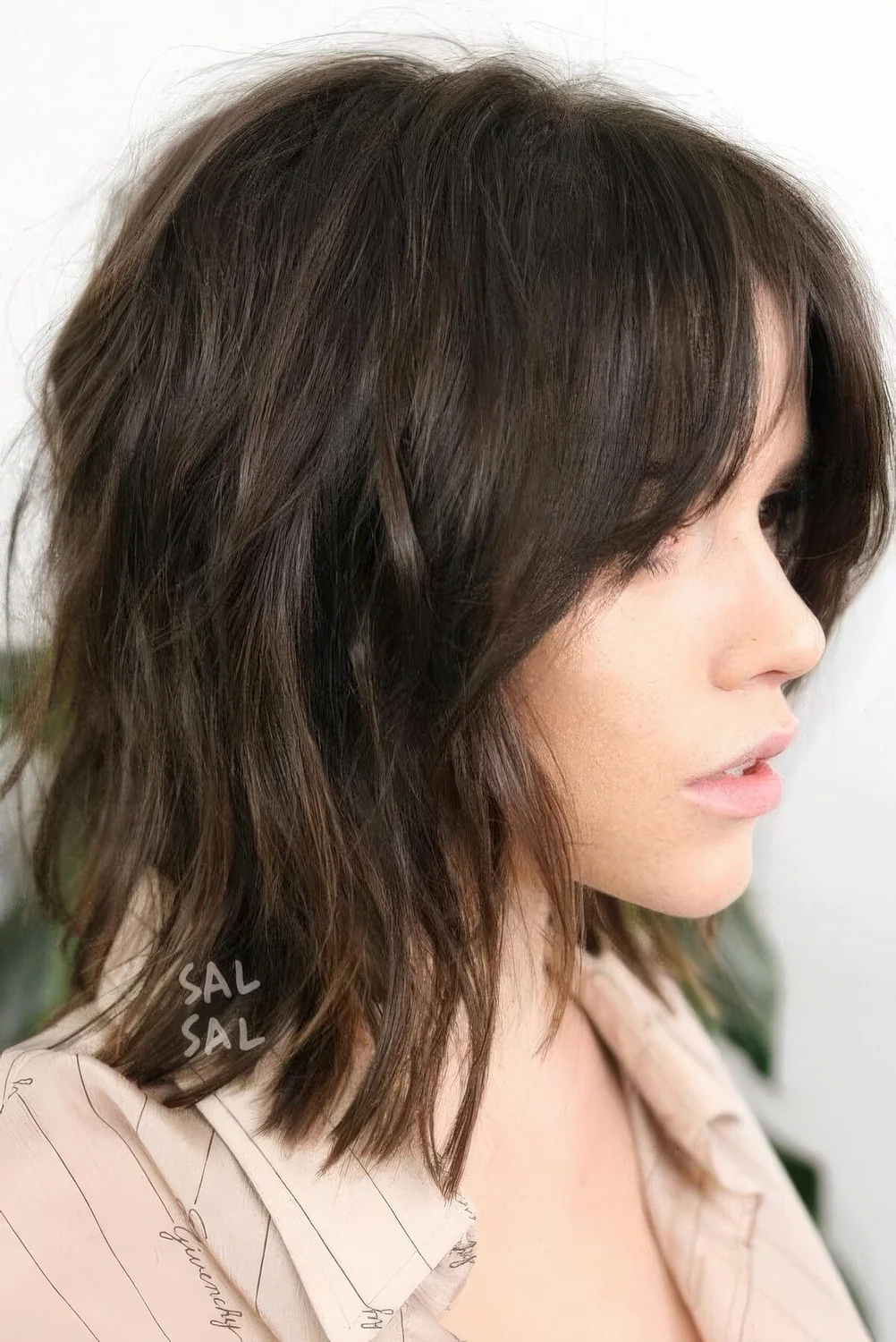 Dark brown long bob with side bangs and messy waves.
