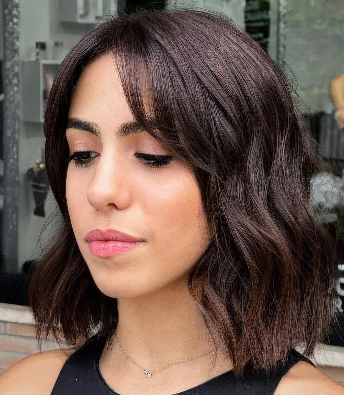 Dark brunette long bob with curtain bangs and waves.