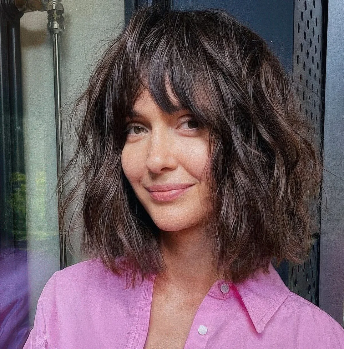 Dark brunette shaggy long bob with a mesys and thick fringe and a lot of messy waves.