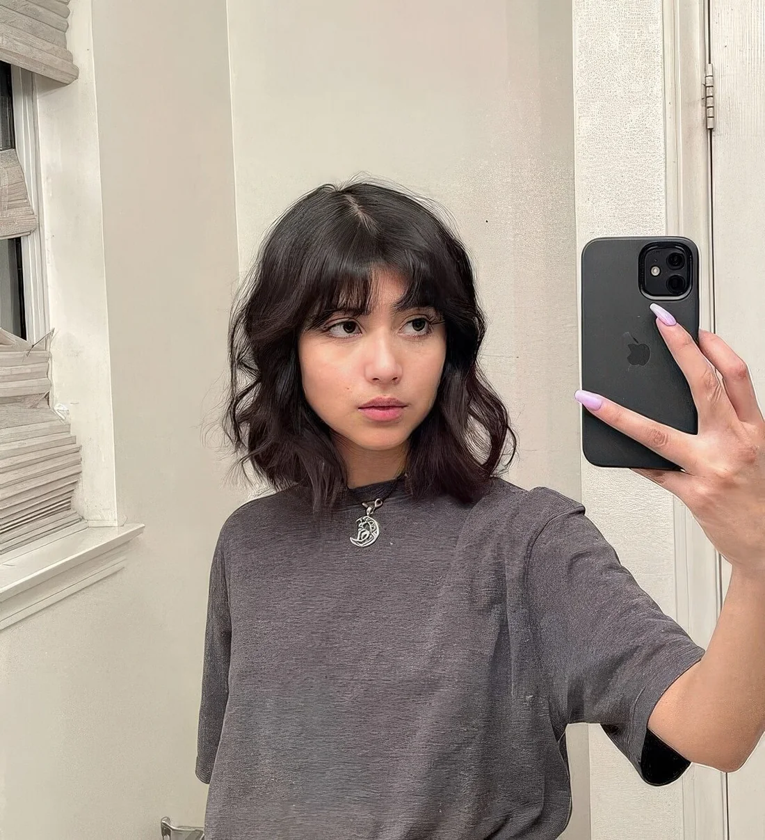 Dark brunette, almost black long bob with bottleneck bangs and middle part.