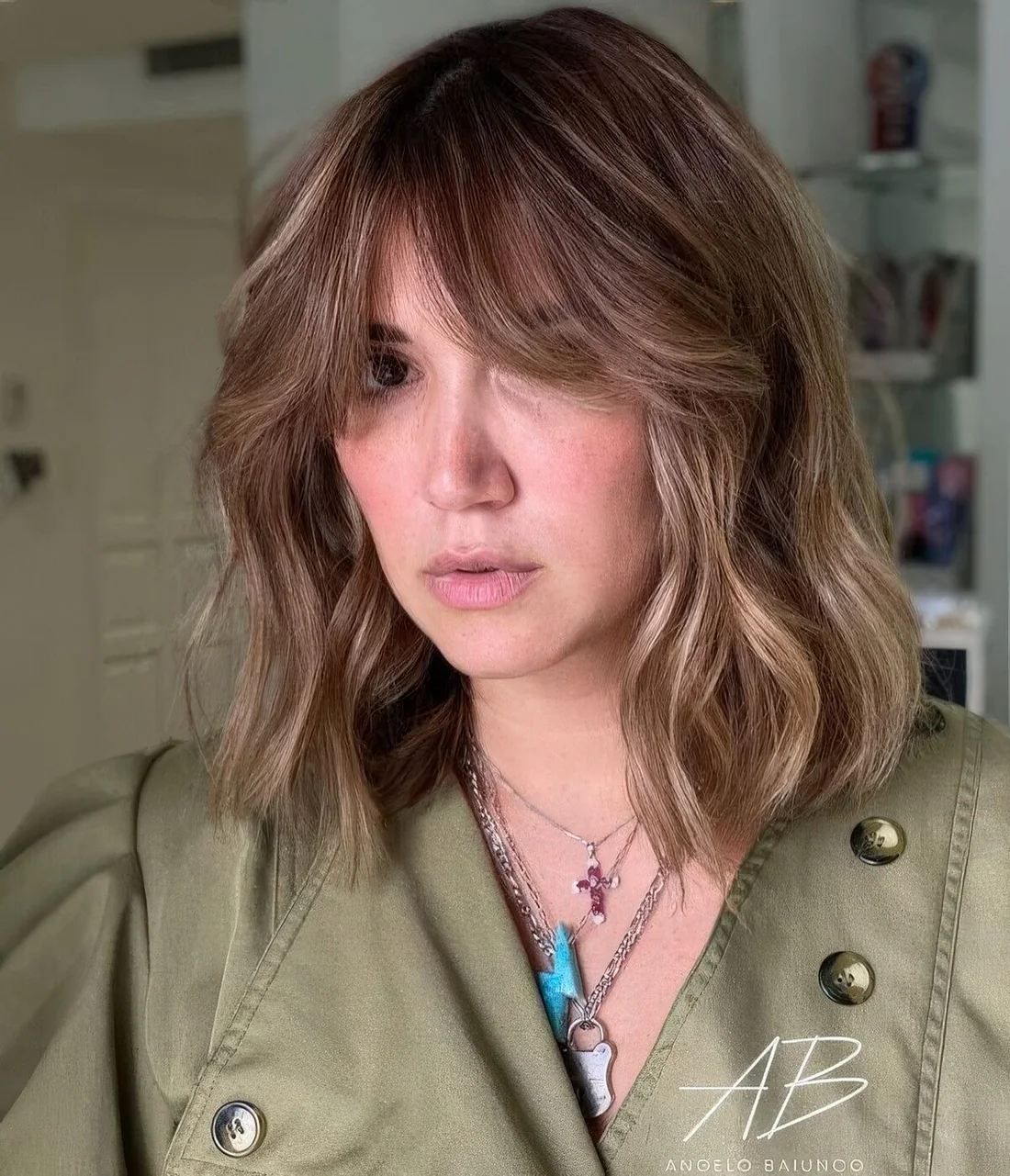 Light brunette long bob with blonde highlights and curtain bangs plus waves.